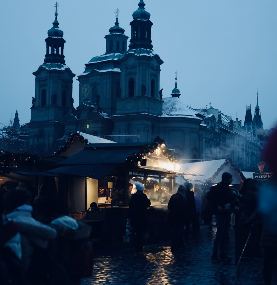 Market stalls on Old Town Square, Prague, at dusk, with St Nicholas Church behind